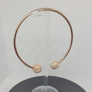 Pave open ended rose gold plated bangle accented by rhinestone studded balls